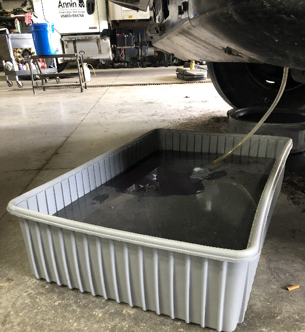 Coolant draining from a truck engine into a Shirley K's Save-A-Spill container