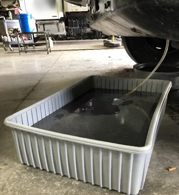 Coolant draining from a truck engine into a Shirley K's Save-A-Spill container